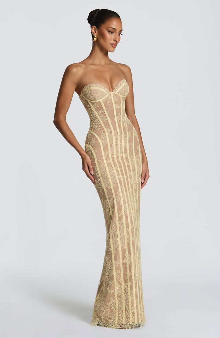 Robe jaune pâle en dentelle portée de trois quarts, mannequin le regard baissé, taille marquée par les baleines. 19