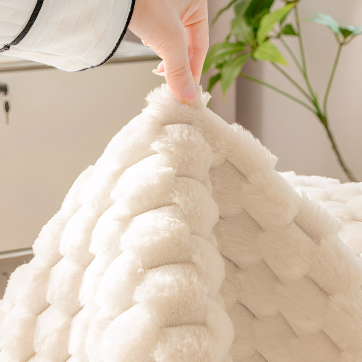 Main soulevant un coin de la housse peluche crème pour montrer le relief du tissu, plante verte en arrière-plan. 5