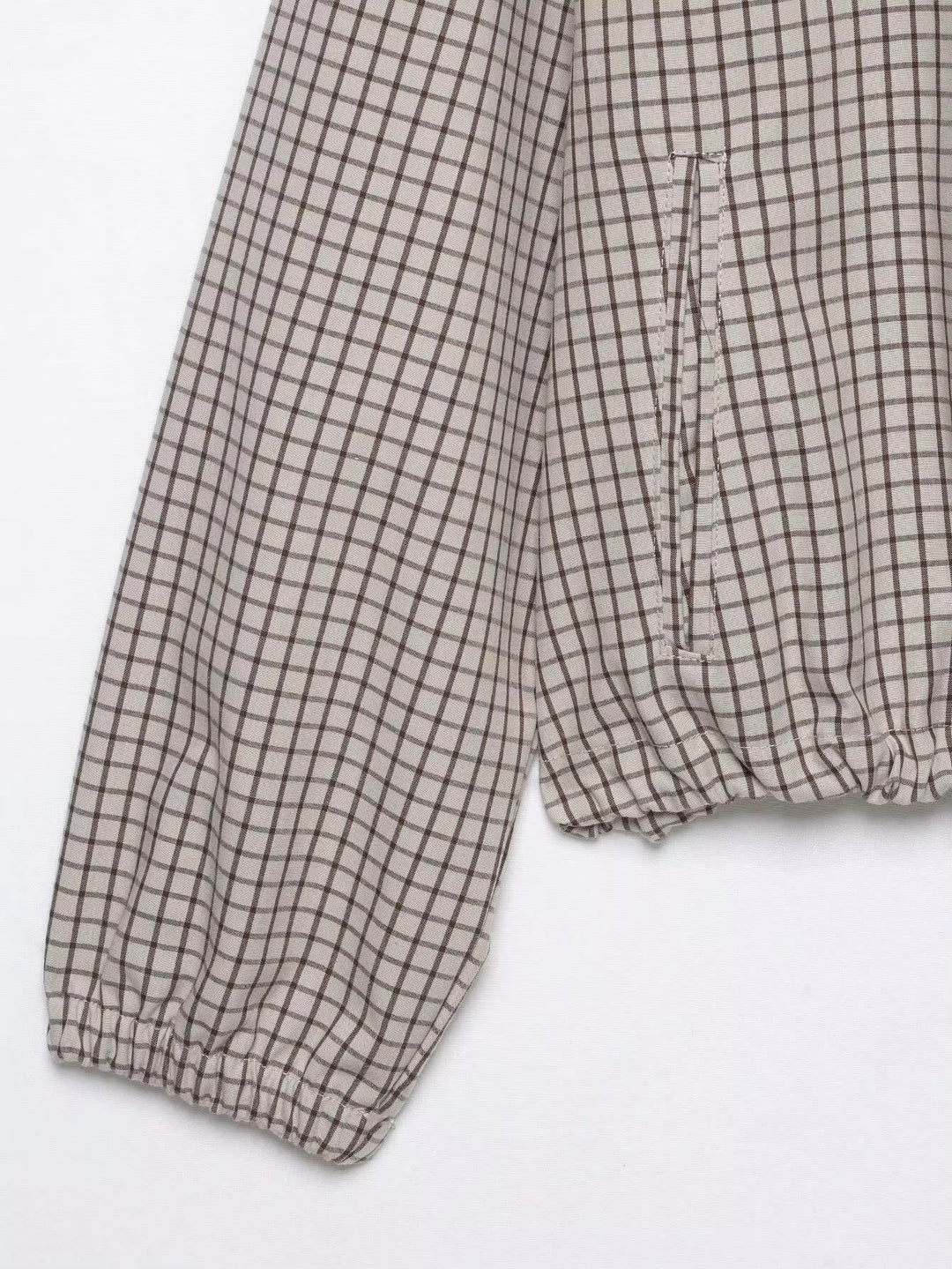Détail à plat d'une manche à poignet élastique et de la poche latérale, avec le bas de la veste froncé. 8