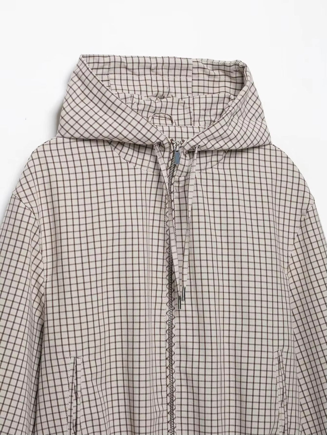 Haut de la veste posée à plat : capuche à carreaux, cordons à embouts métalliques, zip central et ouvertures de poches latérales. 7