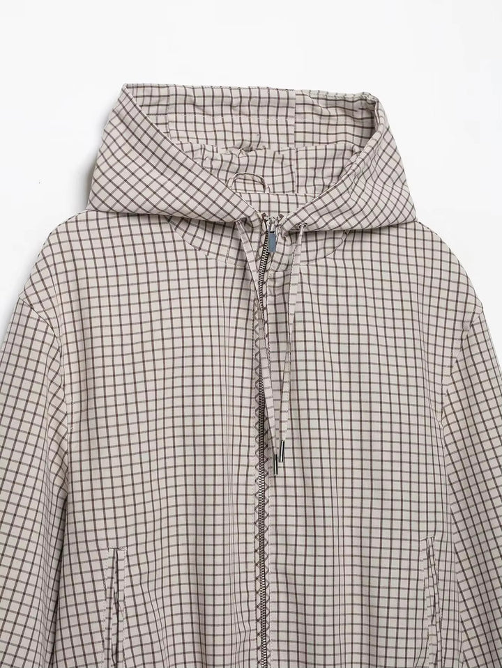 Haut de la veste posée à plat : capuche à carreaux, cordons à embouts métalliques, zip central et ouvertures de poches latérales. 7