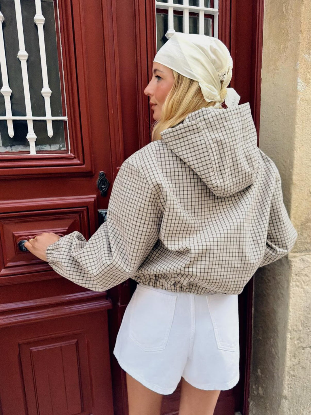 Mannequin de dos, la capuche de la veste à carreaux posée sur les épaules, manches élastiquées et short blanc à poches. 4