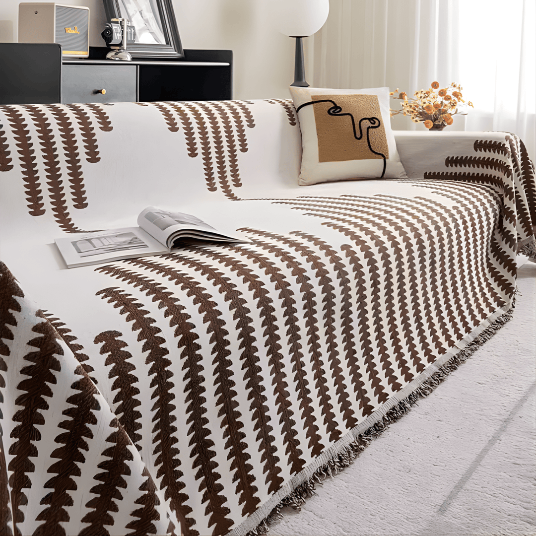 Version marron et crème de la housse sur un canapé, avec coussin à motif visage et franges. 9