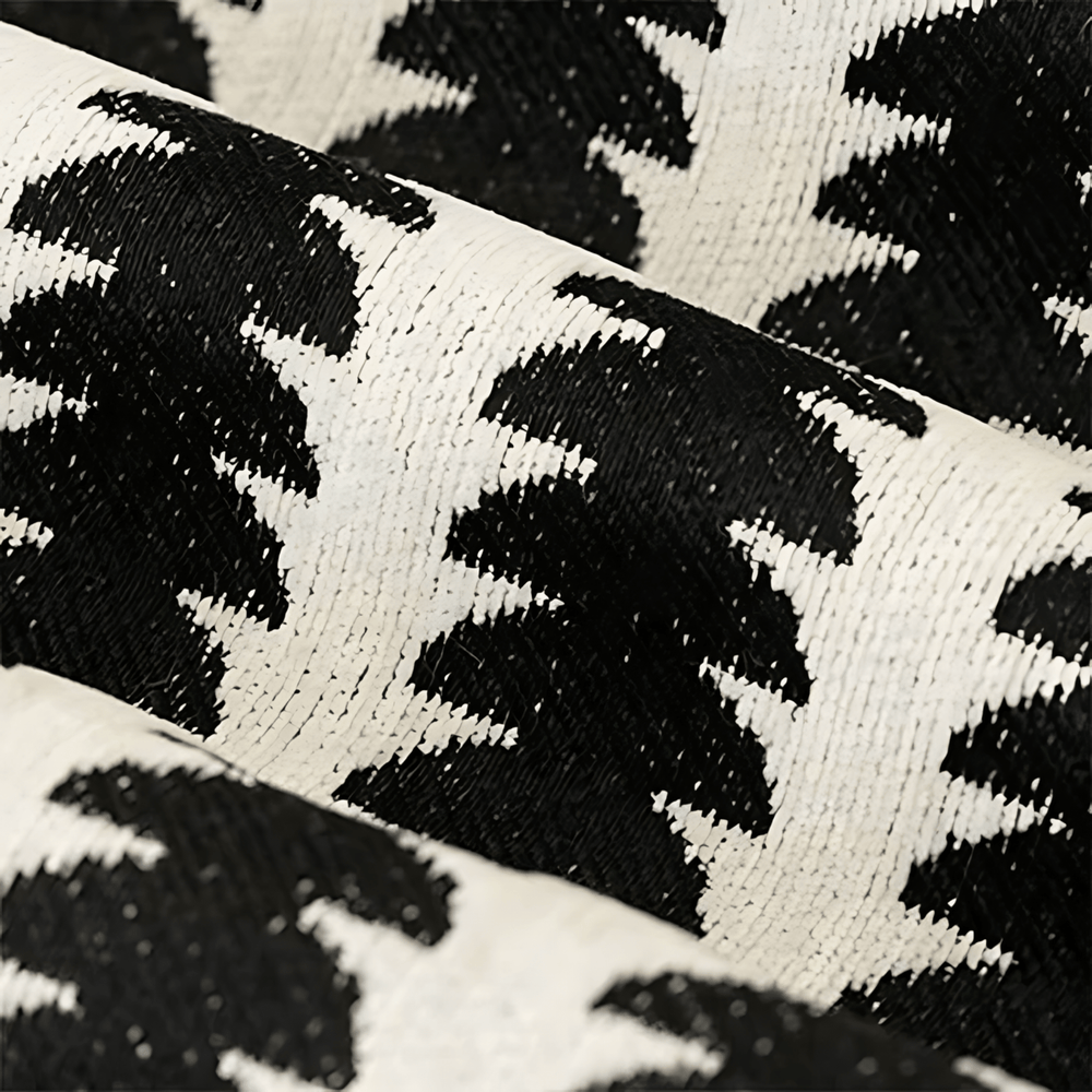Gros plan sur le tissu chenille noir et blanc, montrant le tissage dense et la texture duveteuse du motif. 2