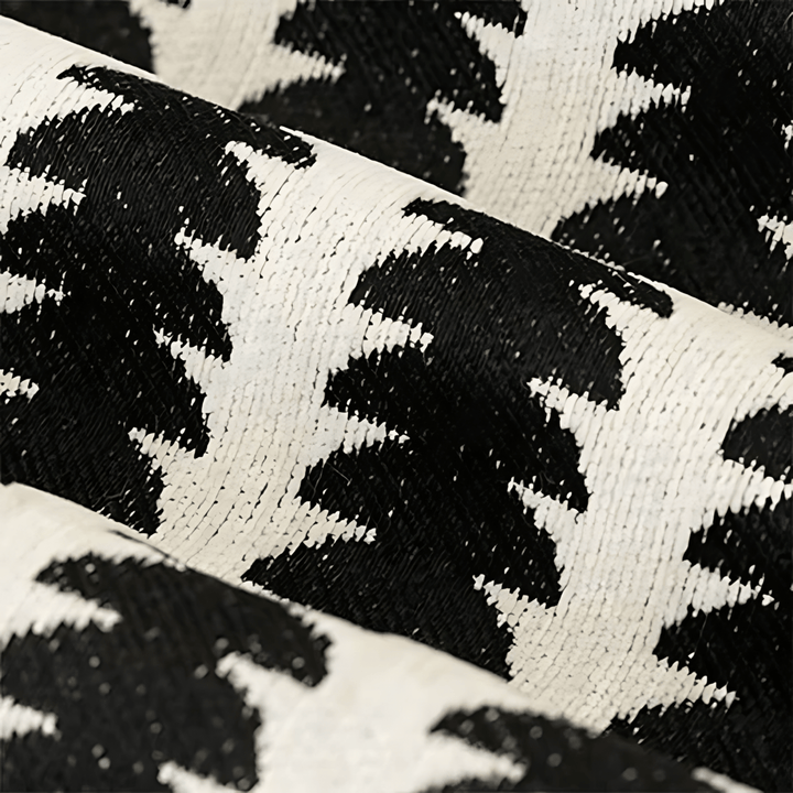 Gros plan sur le tissu chenille noir et blanc, montrant le tissage dense et la texture duveteuse du motif. 2
