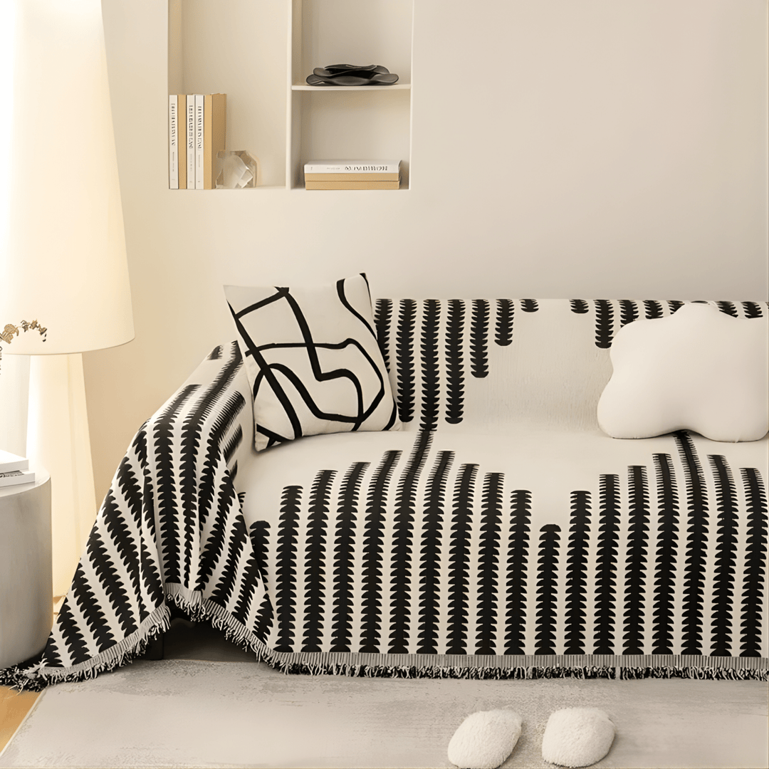 Canapé habillé de la housse noir et blanc à franges, avec un coussin graphique et un coussin nuage blanc. 3