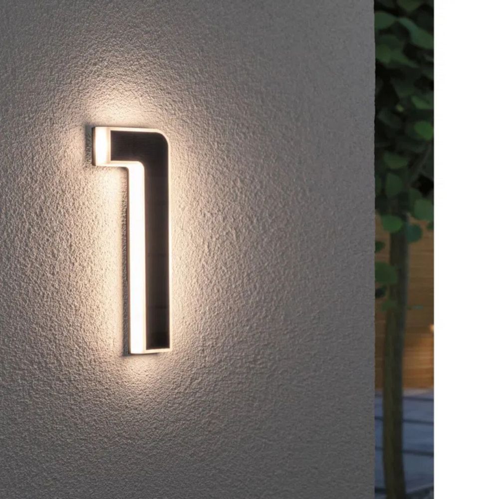 Chiffre 1 éclairé sur un mur de crépi gris, face solaire sombre et contour diffusant une lumière chaude. 2