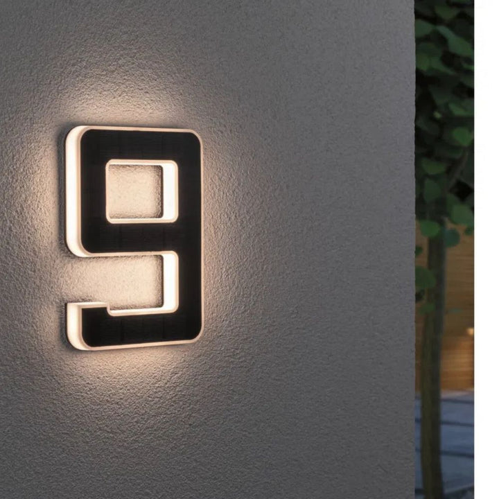 Chiffre 9 éclairé sur un mur gris texturé, face solaire noire et lumière chaude sur le contour. 10