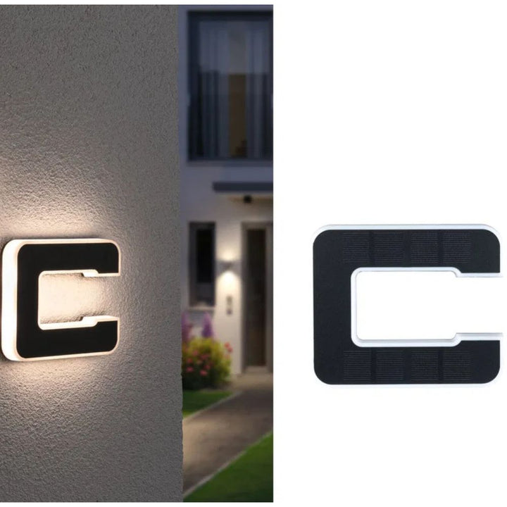 Lettre C en deux vues : allumée sur un mur devant une maison, et panneau solaire noir sur fond blanc. 13