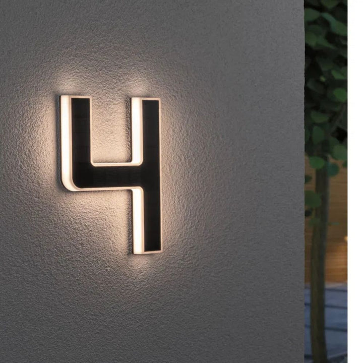 Chiffre 4 lumineux posé sur un mur crépi, face solaire noire et lumière blanc chaud sur les bords. 5