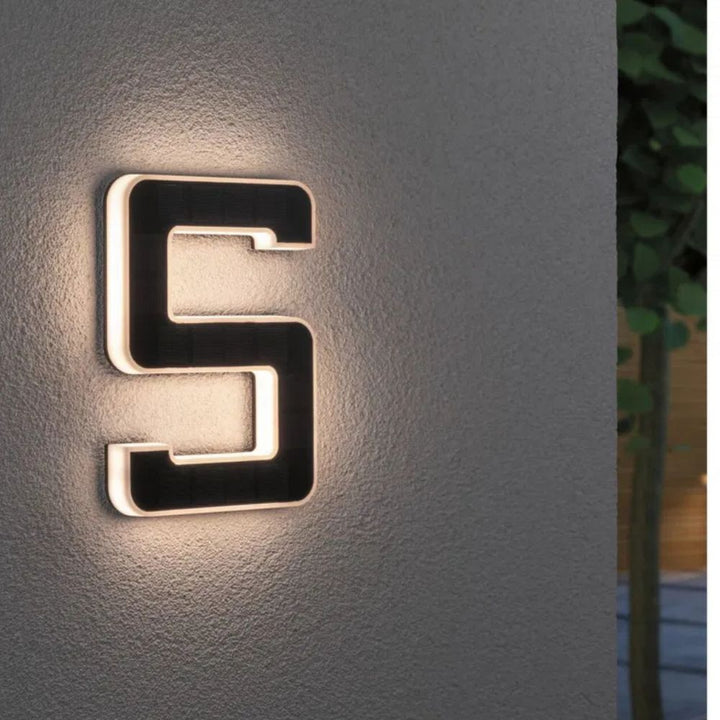 Chiffre 5 éclairé fixé sur un mur gris, cellules solaires noires et contour diffusant une lueur chaude. 6