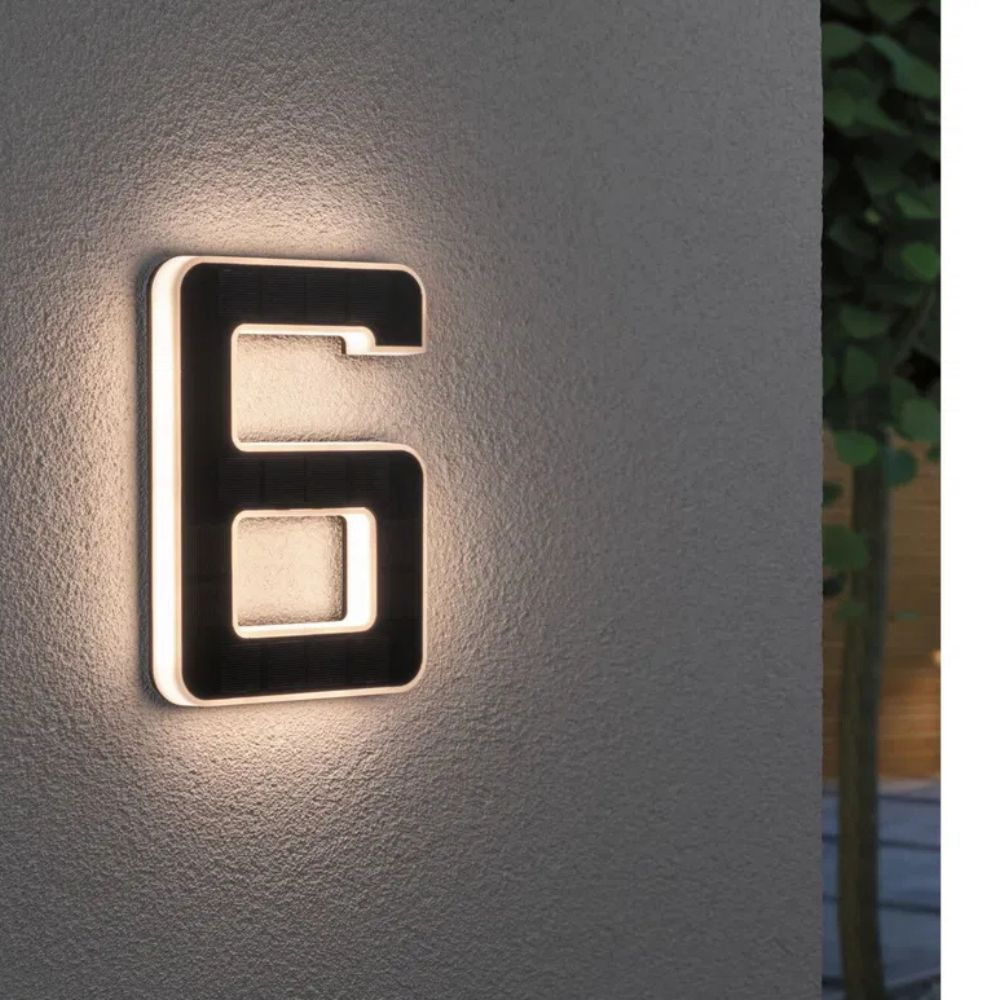 Chiffre 6 lumineux sur un mur de crépi gris, face solaire sombre et halo de lumière blanc chaud. 7