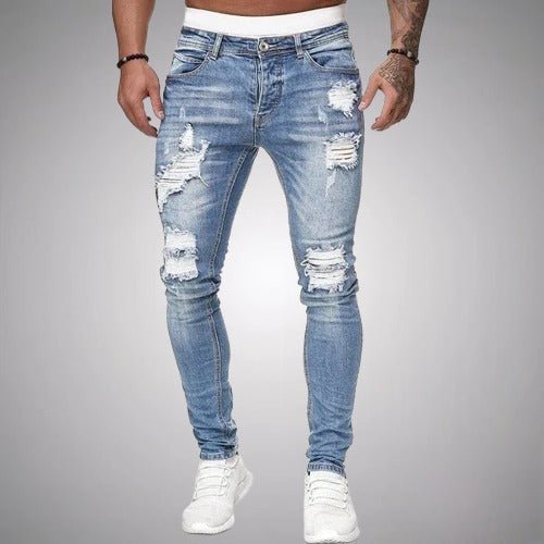 Jean slim déchiré bleu clair délavé porté de face par un homme en baskets blanches, avec accrocs aux cuisses et genoux. 2