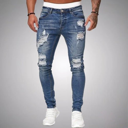 Jean slim déchiré bleu moyen porté de face par un homme en baskets blanches, avec déchirures aux cuisses et aux genoux. 3