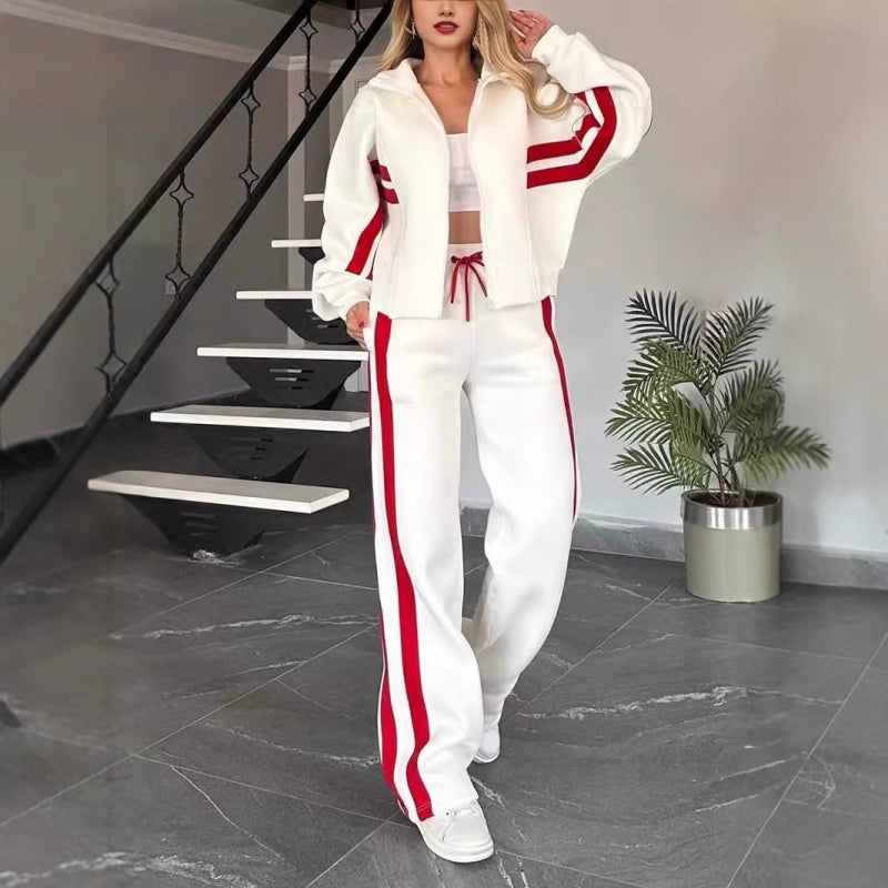 Femme en ensemble blanc à bandes rouges, veste zippée courte et pantalon large, debout près d'un escalier, vue de face. 1