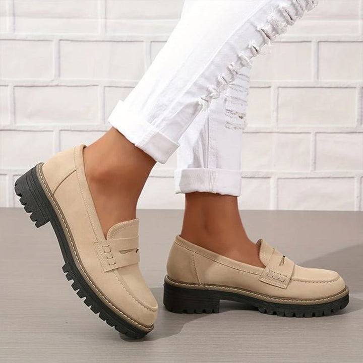 Mocassins beiges portés avec un jean blanc déchiré, un pied levé laissant voir la semelle crantée noire. 3