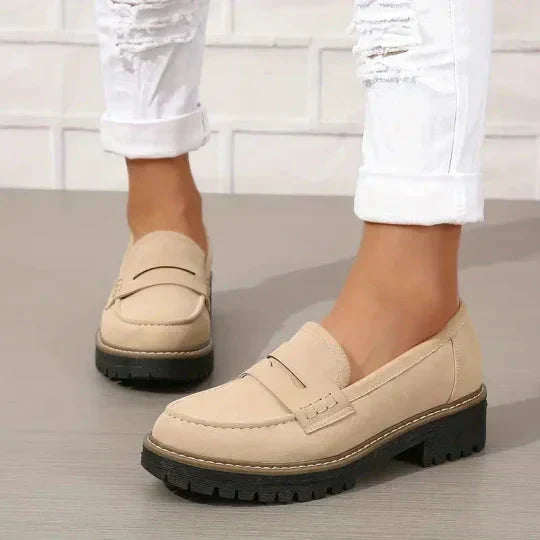 Mocassins beige clair portés avec un jean blanc retroussé, vus de côté sur un sol gris. 7