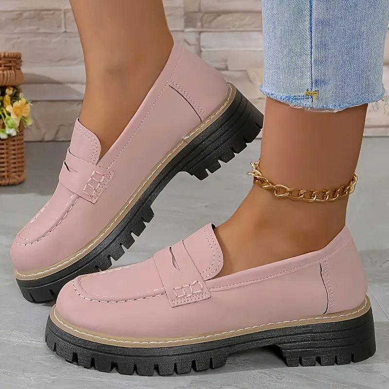 Mocassins roses à l'aspect lisse portés avec une chaîne de cheville dorée, devant un panier d'osier fleuri. 11