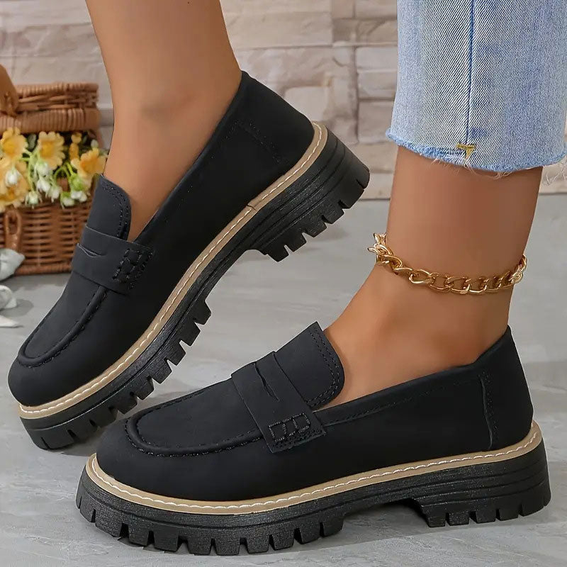 Mocassins noirs à plateforme portés avec une chaîne de cheville dorée et un jean effrangé, panier de fleurs derrière. 12