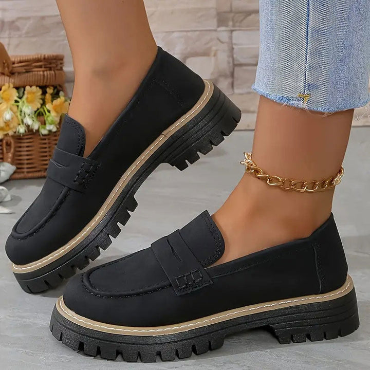 Mocassins noirs à plateforme portés avec une chaîne de cheville dorée et un jean effrangé, panier de fleurs derrière. 12