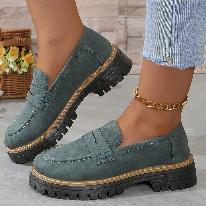 Mocassins vert-gris en daim portés avec une chaîne de cheville dorée, semelle plateforme noire à liseré brun. 15
