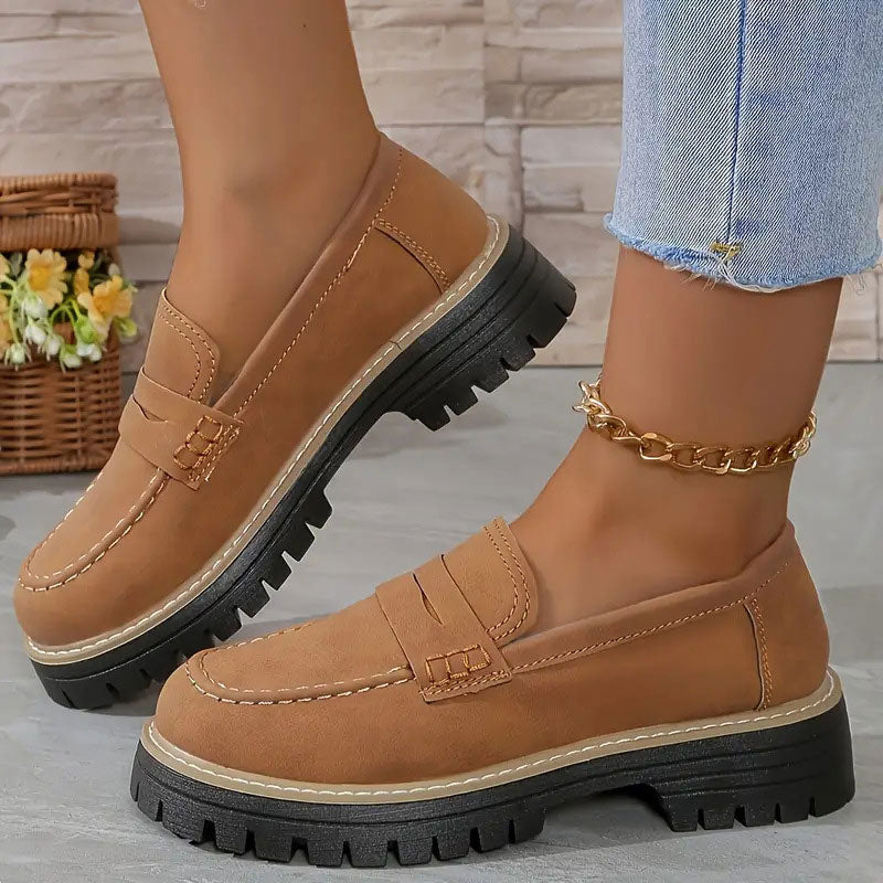 Mocassins camel en daim portés avec une chaîne de cheville dorée, surpiqûres tons sur ton et semelle crantée. 17
