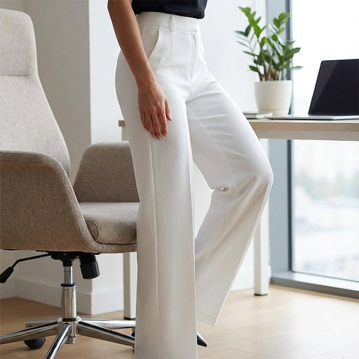Détail du pantalon blanc porté près d'un fauteuil de bureau, montrant la taille haute, le pli et la poche. 14