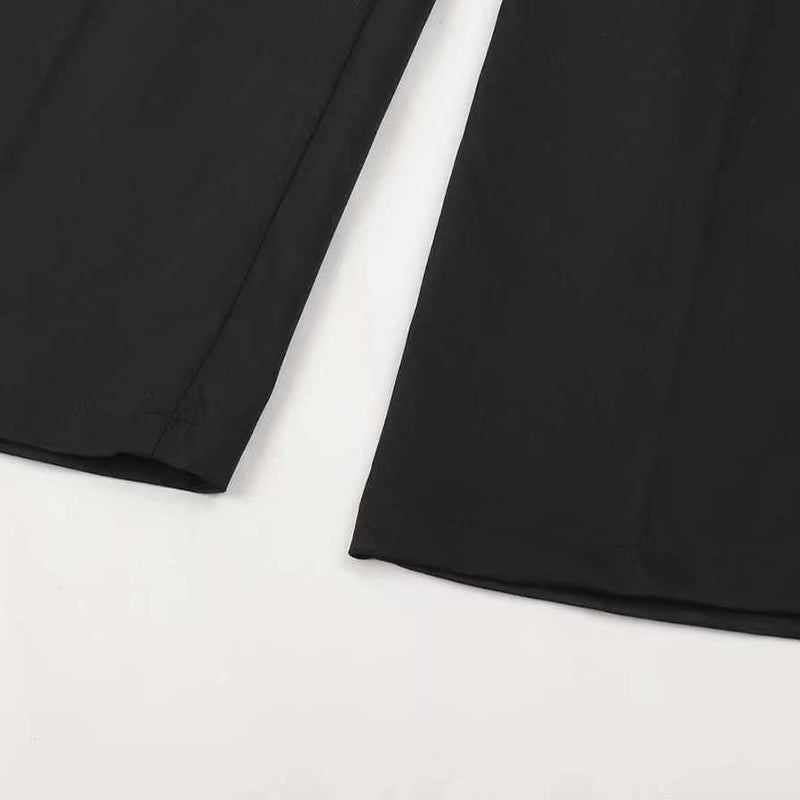 Gros plan à plat sur le bas des jambes du pantalon noir, avec l'ourlet et le pli central visibles. 15