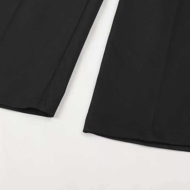 Gros plan à plat sur le bas des jambes du pantalon noir, avec l'ourlet et le pli central visibles. 15