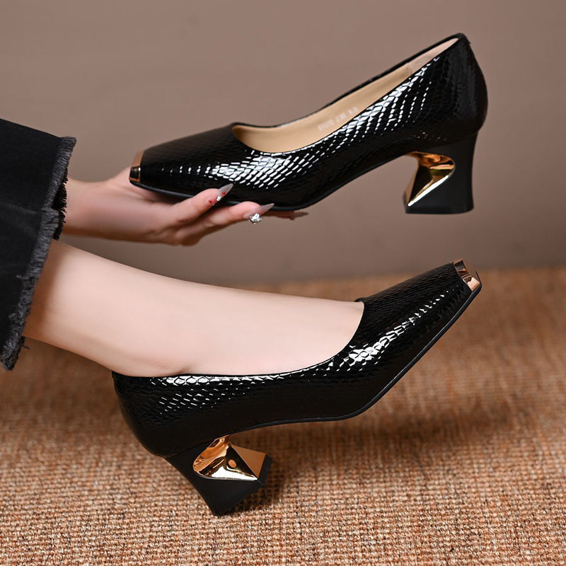 Escarpins noirs imprimé serpent, une paire portée et l'autre tenue en main, montrant le talon doré et l'intérieur beige. 5