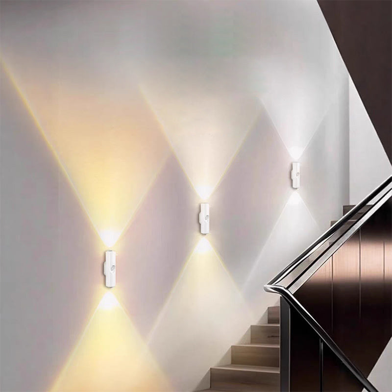 Trois lampes blanches alignées sur le mur d'un escalier, projetant des faisceaux de lumière chaude vers le haut et le bas 8