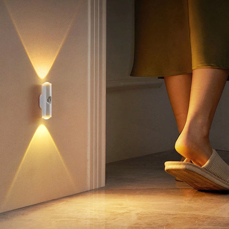 Lampe murale blanche à lumière chaude éclairant un couloir près d'une porte, pieds en chaussons au sol 13