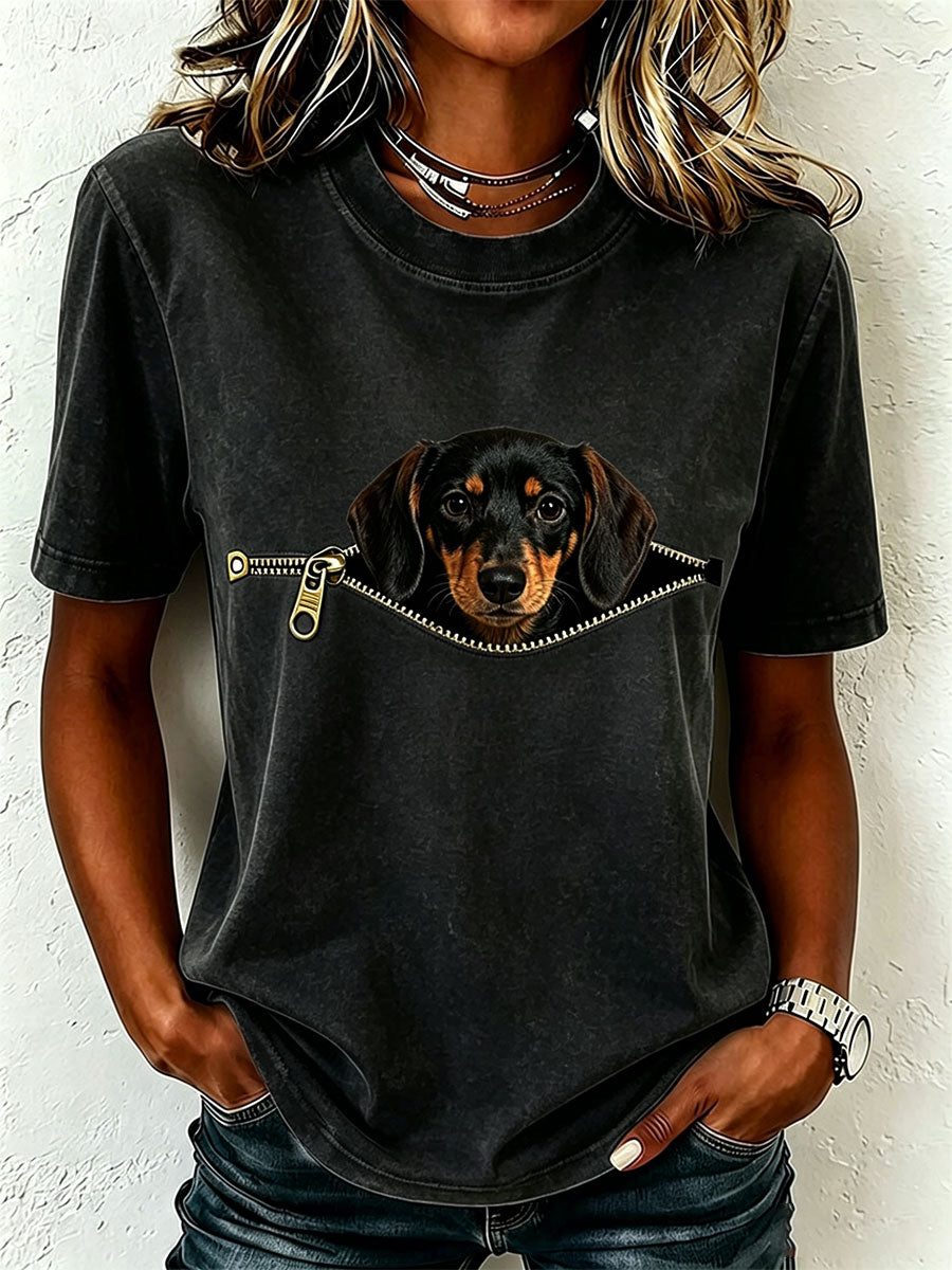 Même t-shirt porté en noir à l'aspect délavé, avec le teckel qui apparaît à travers une fausse fermeture éclair dorée. 3