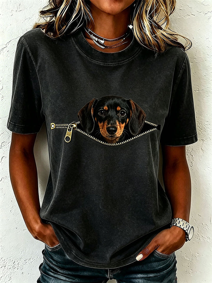 Même t-shirt porté en noir à l'aspect délavé, avec le teckel qui apparaît à travers une fausse fermeture éclair dorée. 3
