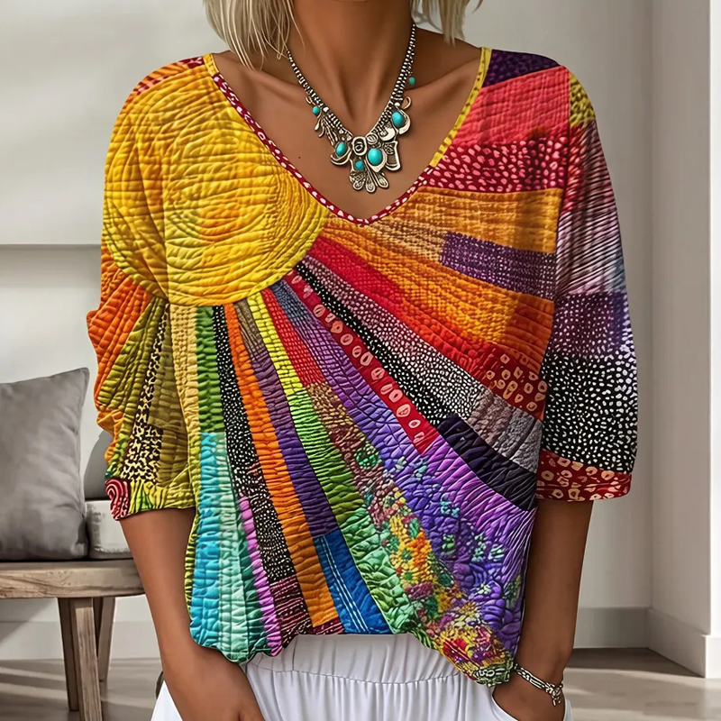 Buste de femme portant la blouse à col en V, patchwork de rayons en jaune, orange, rouge, violet et turquoise, avec un collier. 1
