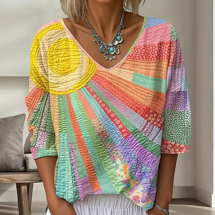 Blouse patchwork aux couleurs pastel, soleil jaune vif et rayons multicolores, portée en plan rapproché avec un collier turquoise. 6