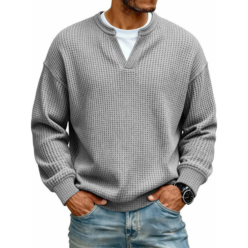 Haut en maille gaufrée gris moyen, encolure en V sur t-shirt blanc, mains dans les poches du jean, vue de face. 17