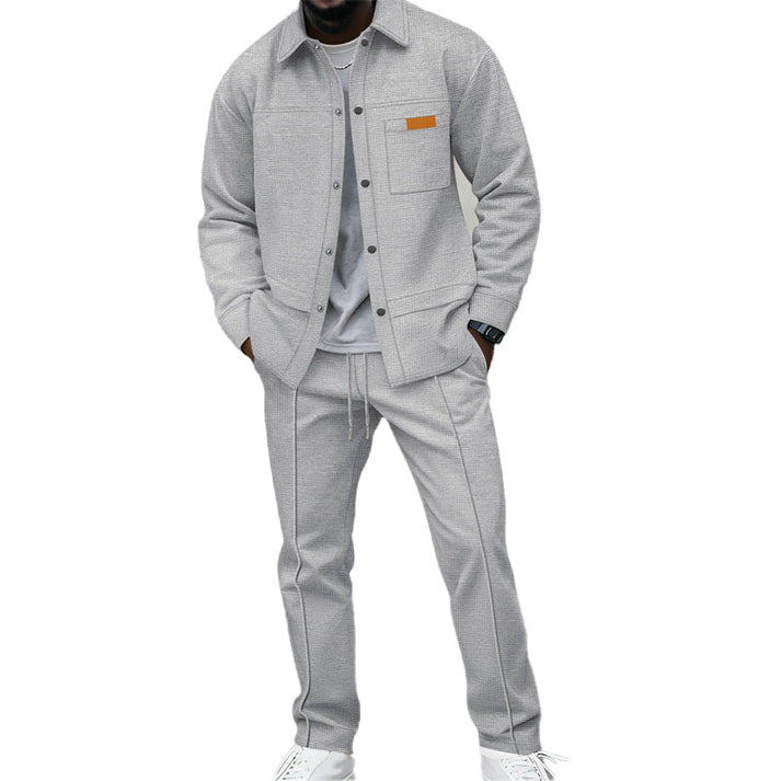 Même ensemble en gris clair porté par un homme, chemise ouverte sur t-shirt gris, pantalon à cordon 2