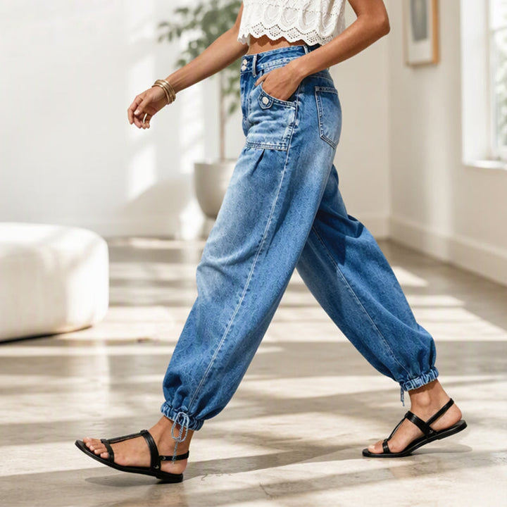 Femme en marche vue de profil, jean barrel bleu à jambes bouffantes, lien noué à la cheville, dans un intérieur lumineux. 7