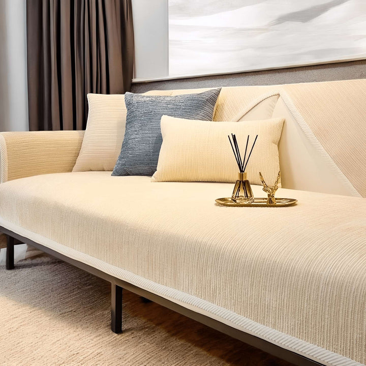 Housse crème à fines côtes sur un canapé, coussins crème et bleu-gris, diffuseur de parfum et plateau doré posés sur l'assise. 4