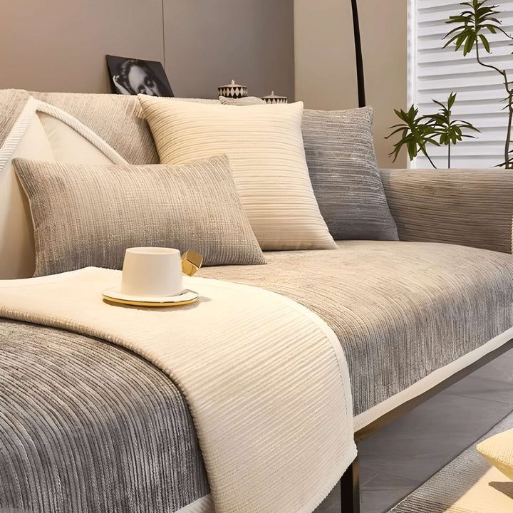 Housse beige et grise à côtes sur un canapé, avec tasse blanche posée sur le bord crème et coussins assortis. 3