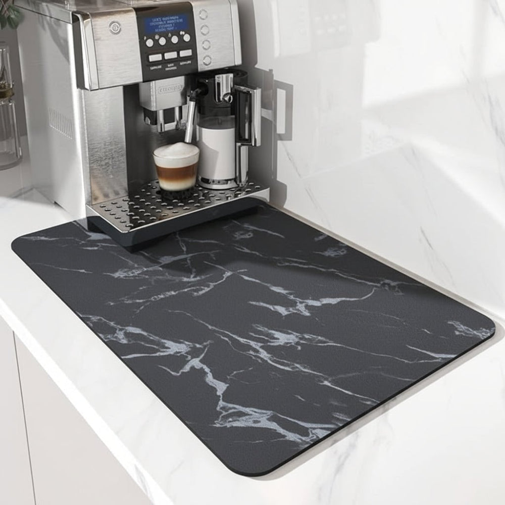 Tapis noir à motif marbré blanc sous une machine à café, vu de l'avant sur un plan de travail clair. 4