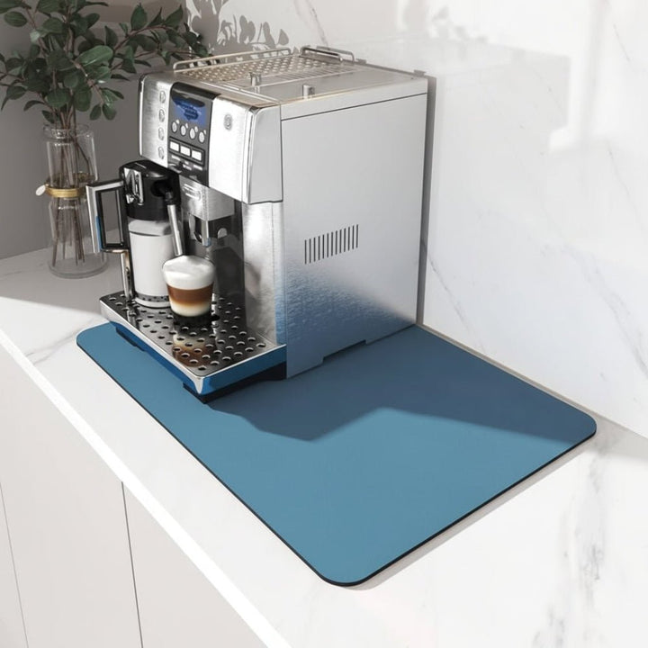 Tapis bleu uni posé sur un plan de travail en marbre blanc, sous une machine à café avec un cappuccino. 1