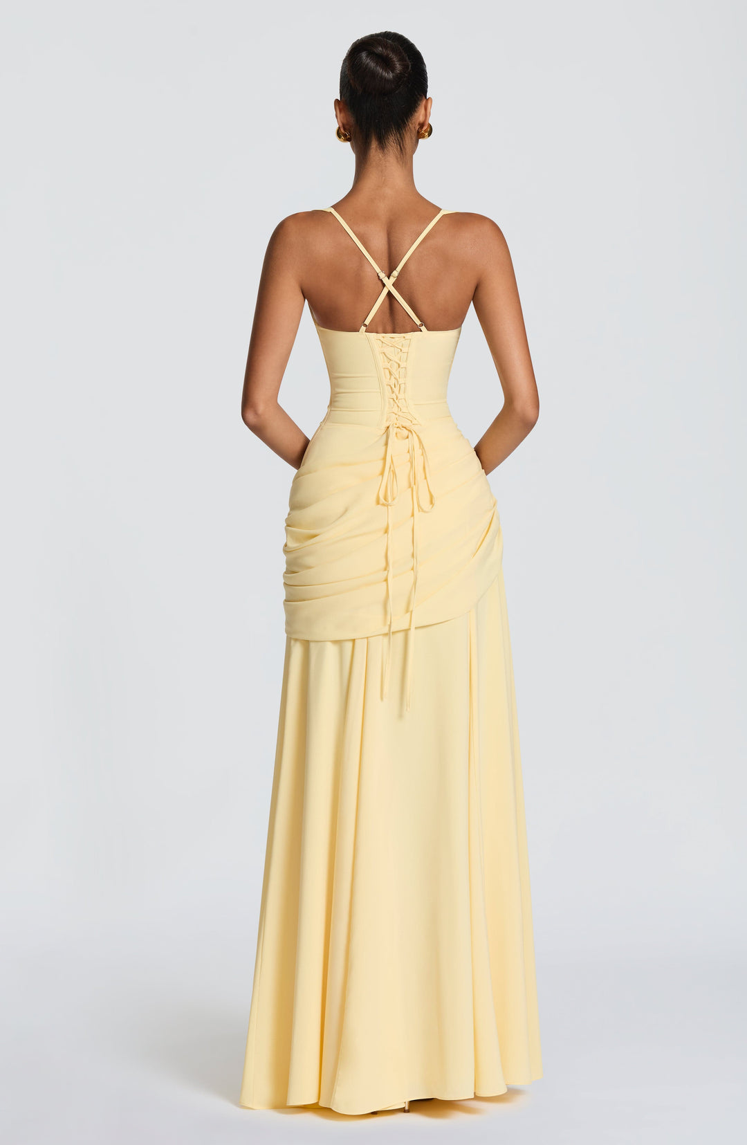 Vue de dos de la robe jaune pâle : corset lacé, fines bretelles croisées et drapé de mousseline sur les hanches. 2