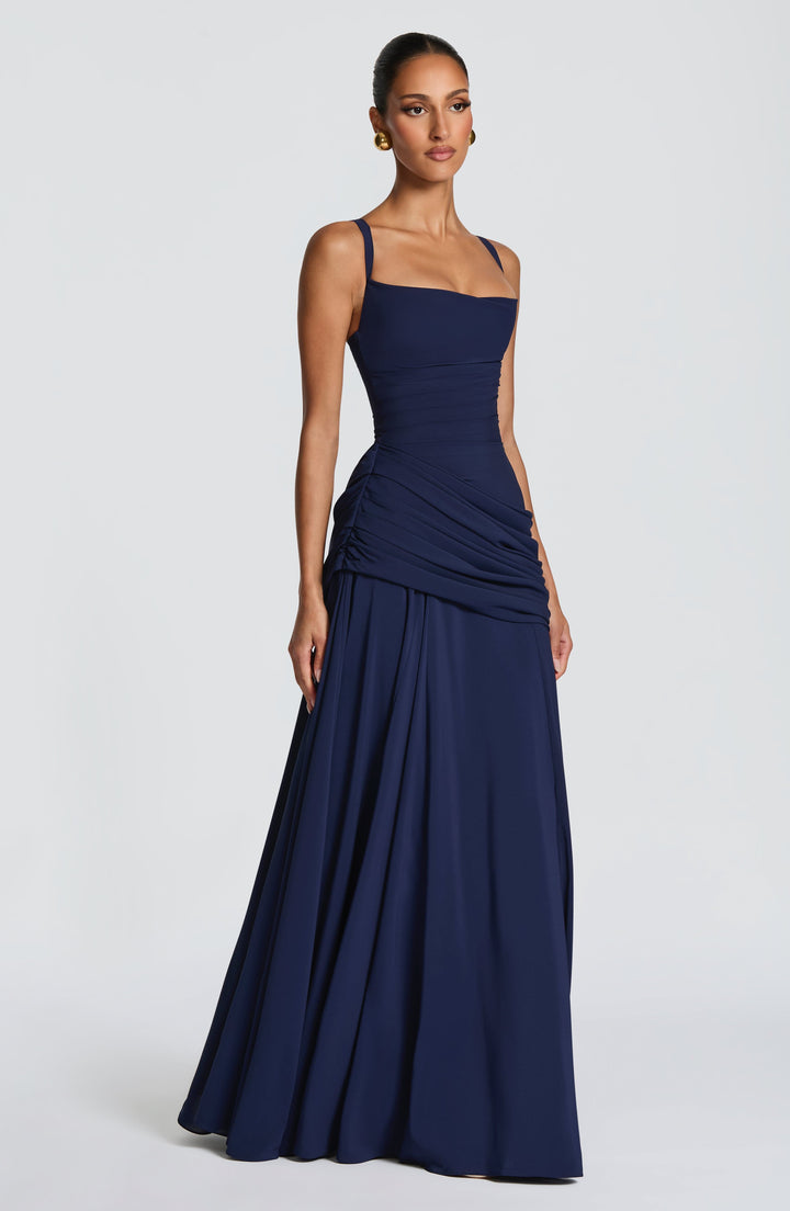 Robe longue bleu marine portée de trois quarts, avec fines bretelles, taille ruchée et jupe fluide évasée. 12