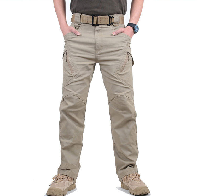 Vue de face du pantalon beige porté avec ceinture tactique, mains dans les poches, poches zippées visibles 1