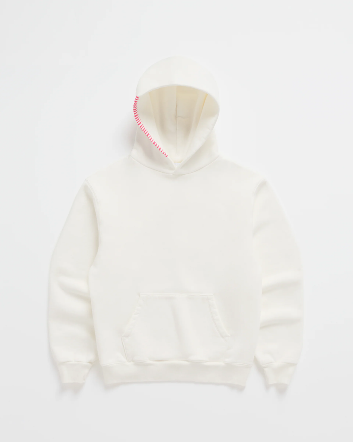 Sweat à capuche blanc cassé posé à plat, avec une couture rose vif en zigzag sur le bord de la capuche. 2