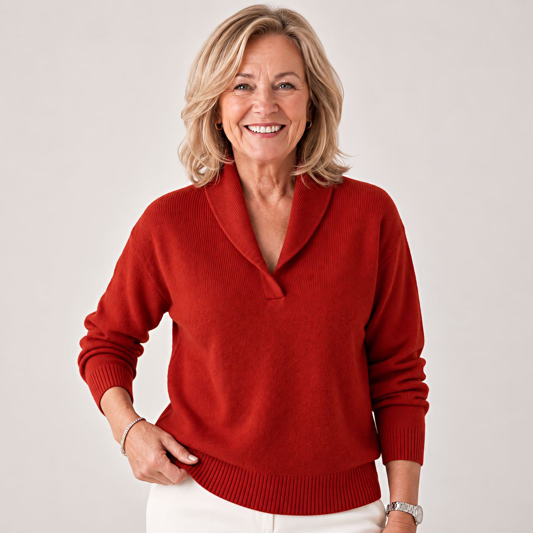 Femme riant, une main sur la hanche, portant le pull rouge brique à col châle et pantalon blanc. 7