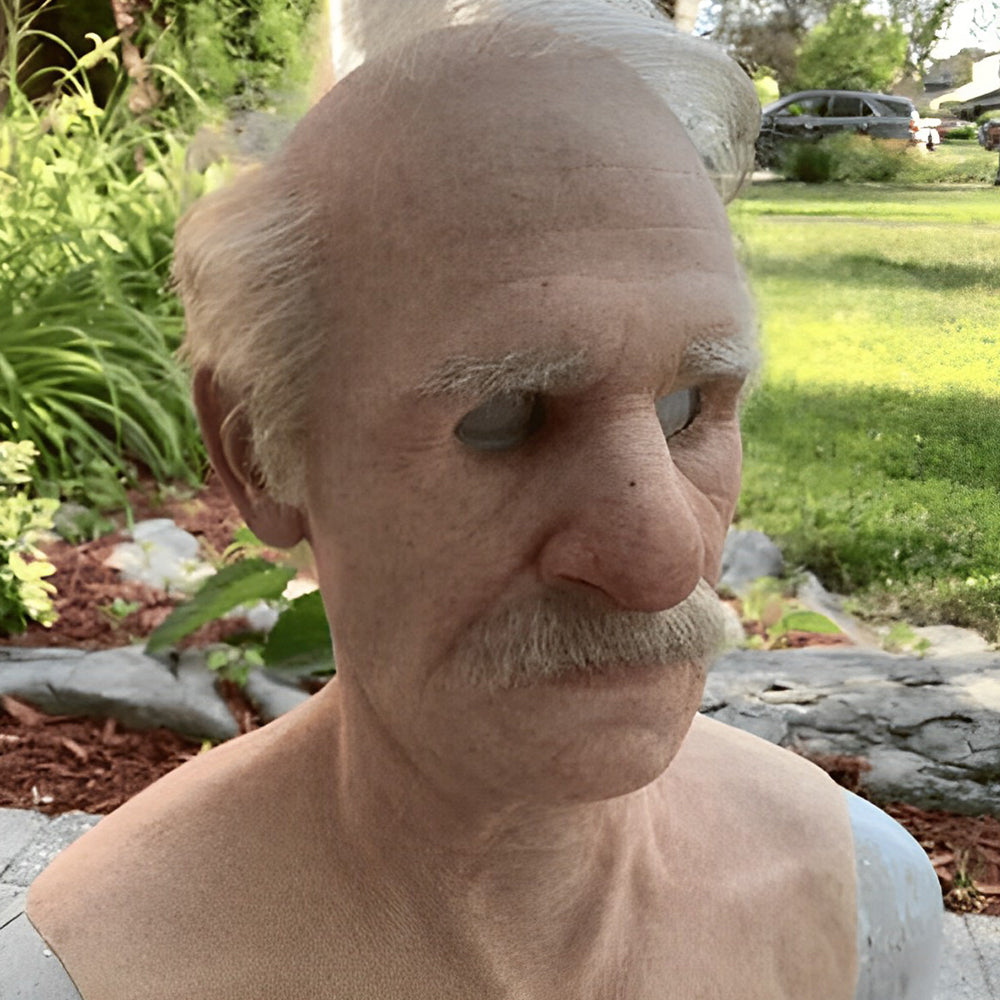 Masque de vieil homme chauve aux cheveux gris et à la moustache, vu de trois quarts dans un jardin. 21