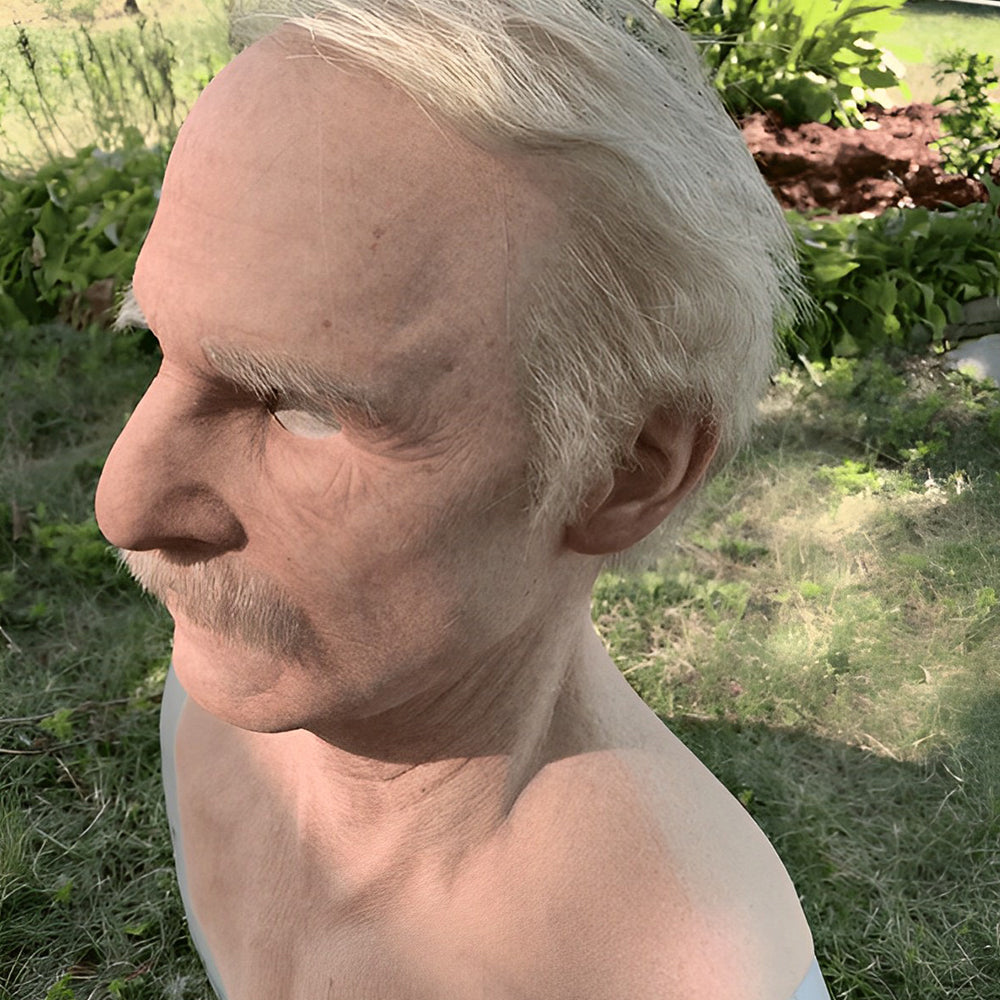Masque de vieil homme vu de profil en extérieur, cheveux blancs, sourcil broussailleux et moustache, sur fond de verdure. 8